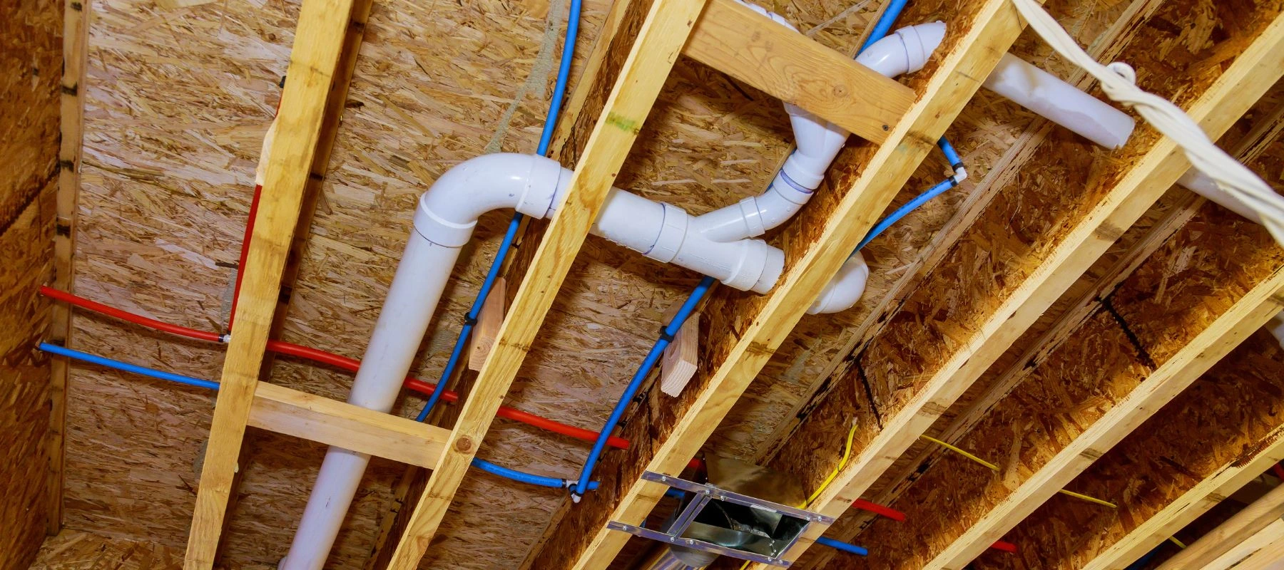 Comprehensive whole-home plumbing installation featuring organized hot and cold water lines and main waste drainage in the ceiling joists